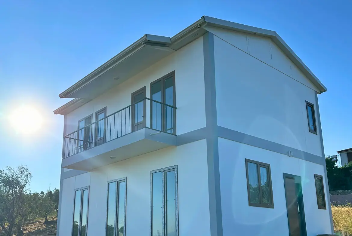 Balkonlu beyaz dış cepheli iki katlı prefabrik ev